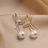 Pendientes de perla con lazo brillante en dorado