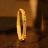 Pulsera tipo brazalete con piedras preciosas verdes y doradas y patrón floral de estilo étnico